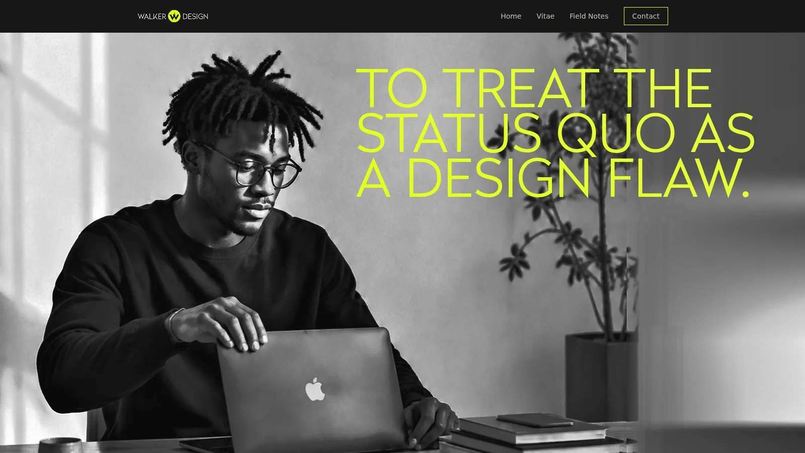 A young man in glasses opening a laptop at a desk, in black and white.