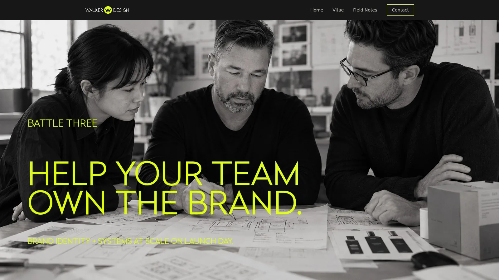 A team reviewing brand system boards around a table, in black and white.